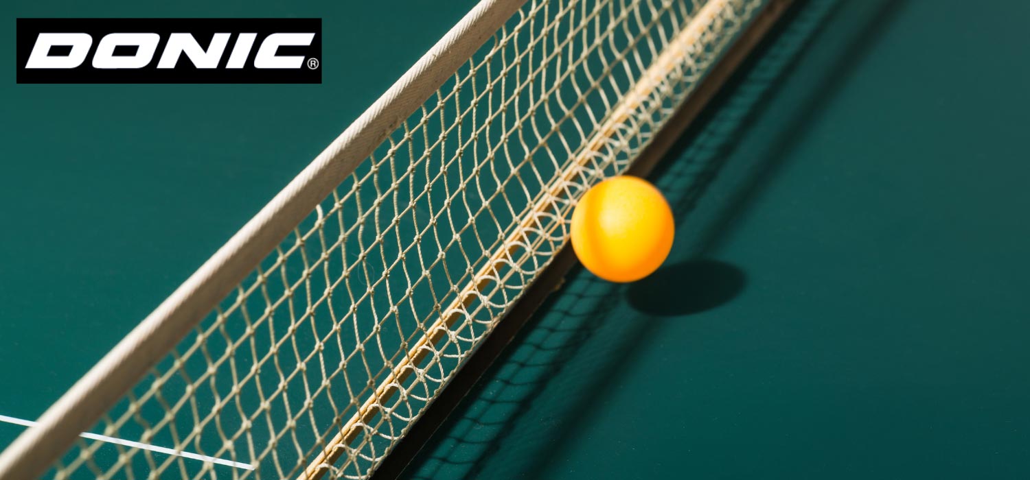 Nahaufnahme gruene Tischtennisplatte mit gelbem Ball